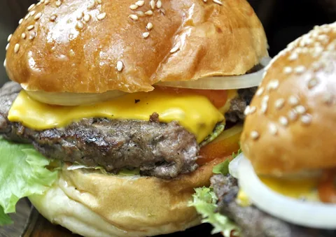 Cheeseburger com folhas, cebola e pão tostado.